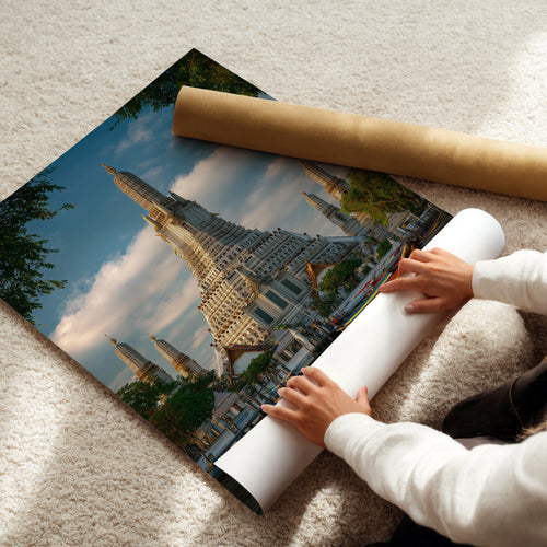Person rolling out a Bangkok poster showcasing Wat Arun Temple, ready for display.