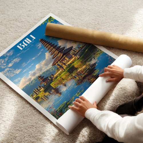 Person unrolling a Bali poster showcasing a traditional Indonesian temple by a lake, perfect for travel enthusiasts.